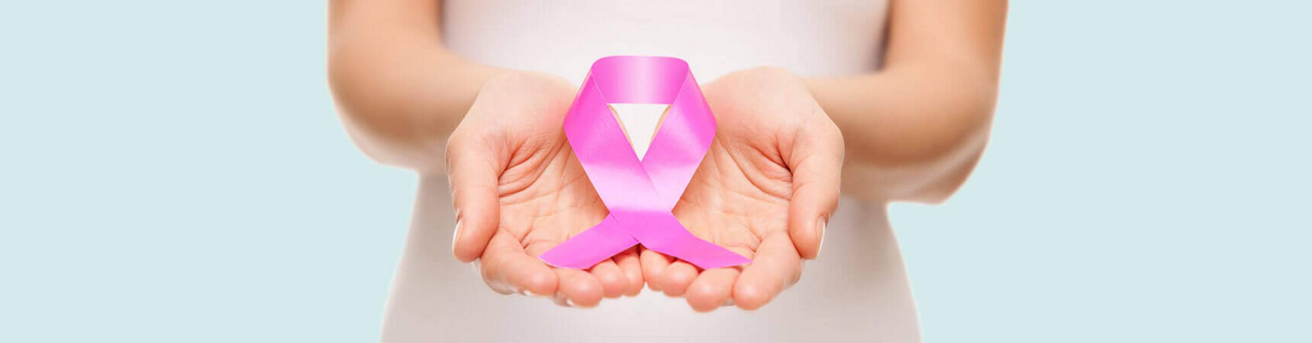 Zwei Hände halten eine pinke Schleife, das Symbol der Brustkrebsfrüherkennung.