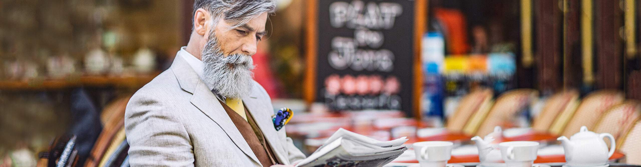 Mann sitzt in einem Cafe und liest Zeitung.