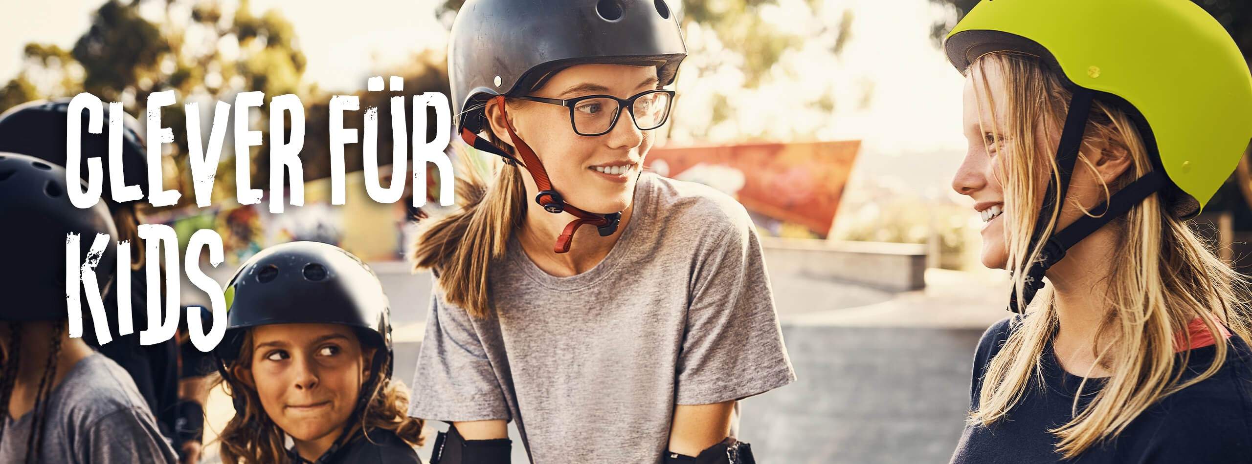 Mädchen mit Helm beim Skateboardfahren. Im Hintergrund steht der Slogan Clever für Kids.