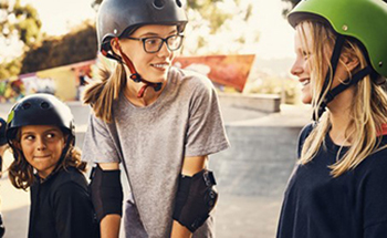 Mädchen mit Helm fahren Skateboard