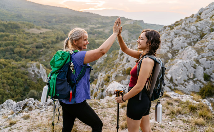 Zwei Frauen klatschen sich nach Erreichen eines Ziels auf einer Wanderschaft ab