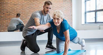 Physiotherapeut hilft Seniorin bei einer Übung